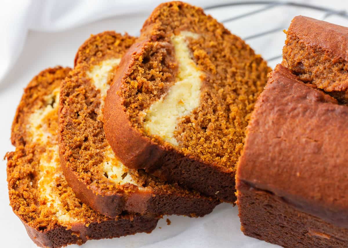 This pumpkin cream cheese bread is a delicious dessert to make this fall! It has the perfect amount of pumpkin spice flavor with an amazing cream cheese filling. The best pumpkin cream cheese bread sliced on a plate.