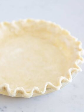 Pie crust fluted in a glass baking dish.