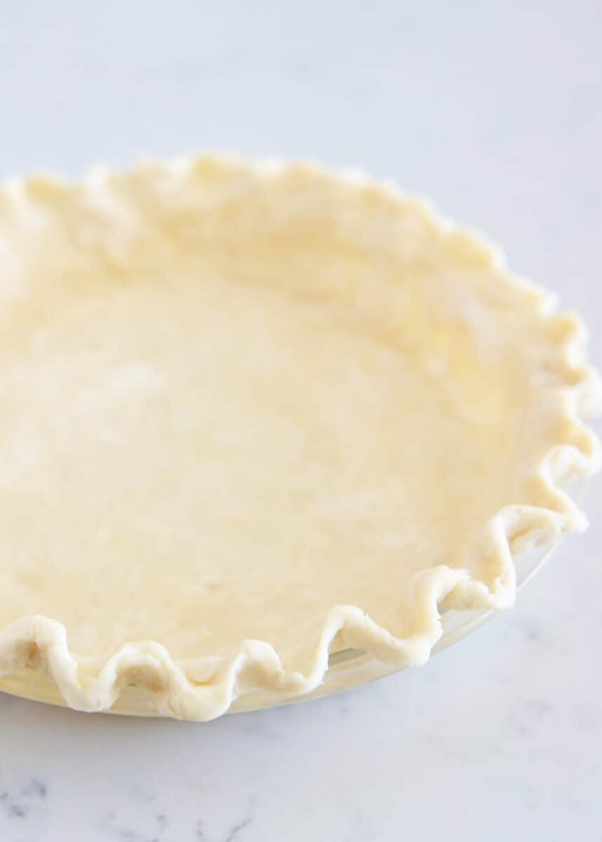 Pie crust fluted in a glass baking dish.