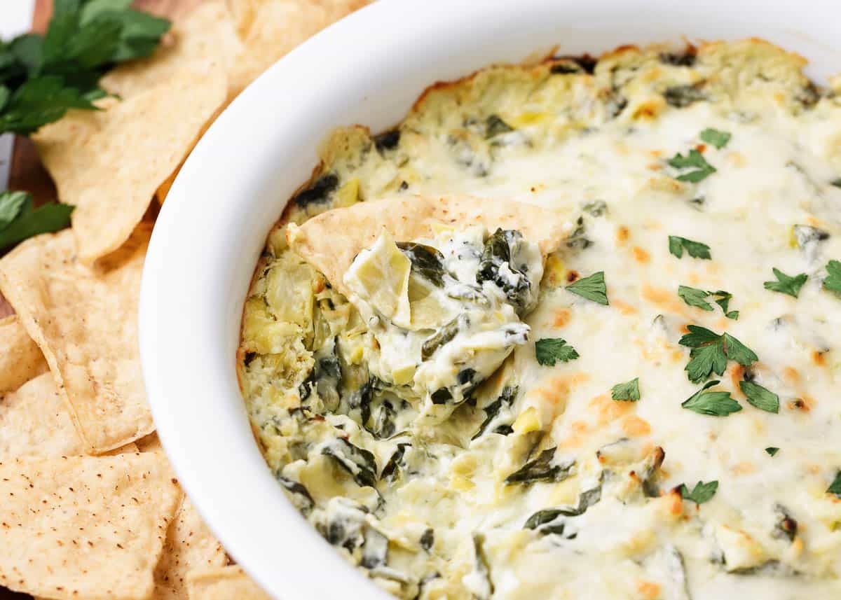 Spinach artichoke dip baked in a white baking dish.