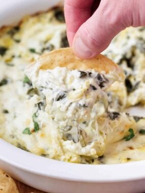 Spinach artichoke dip on a tortilla chip.
