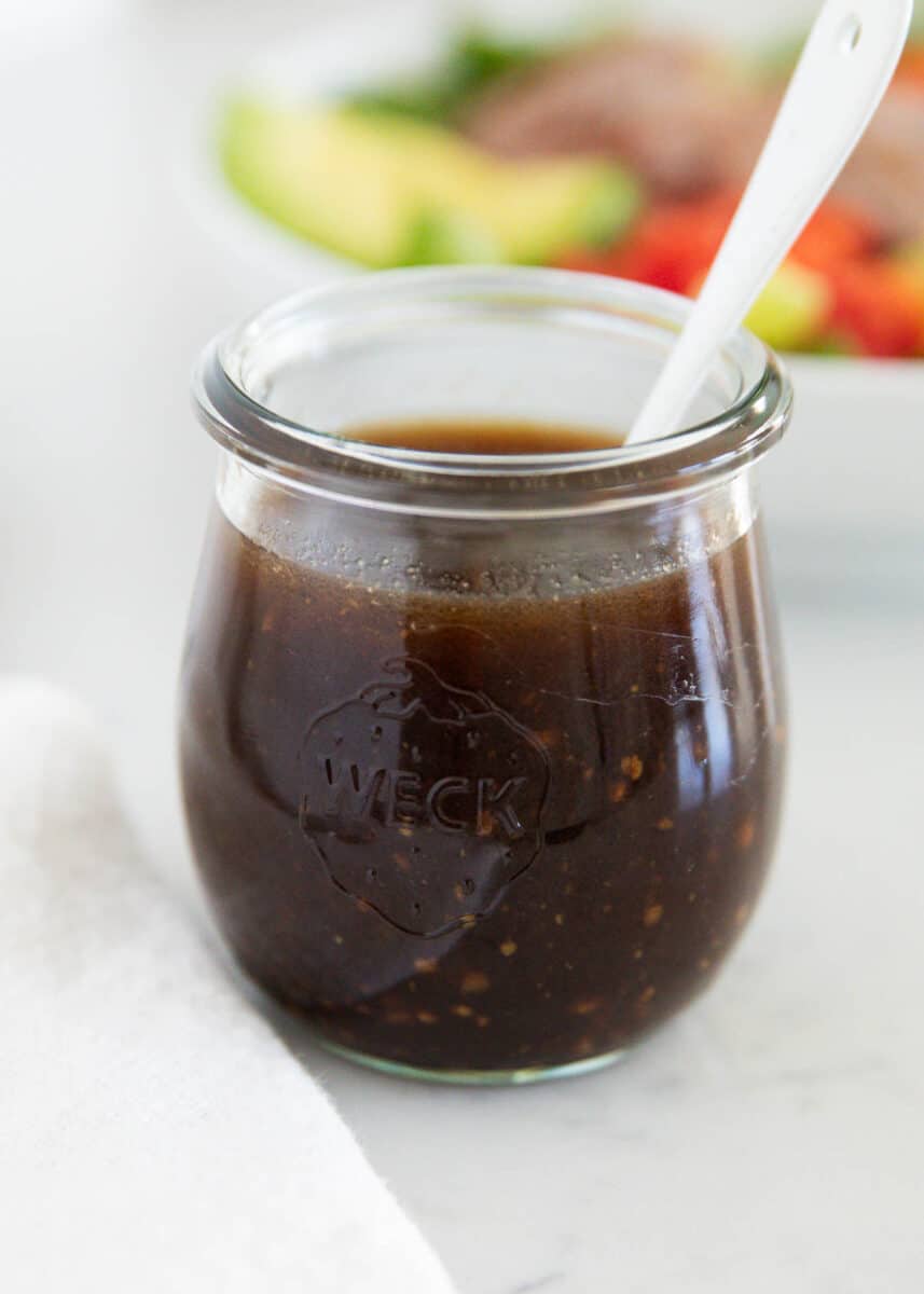 Balsamic vinaigrette in a glass jar with salad.