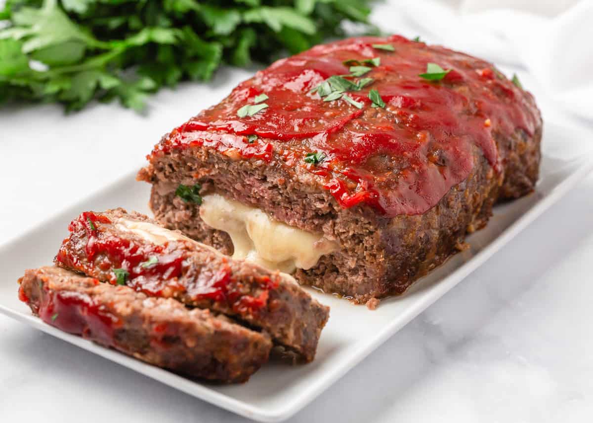 Sliced stuffed meatloaf on white plate. 