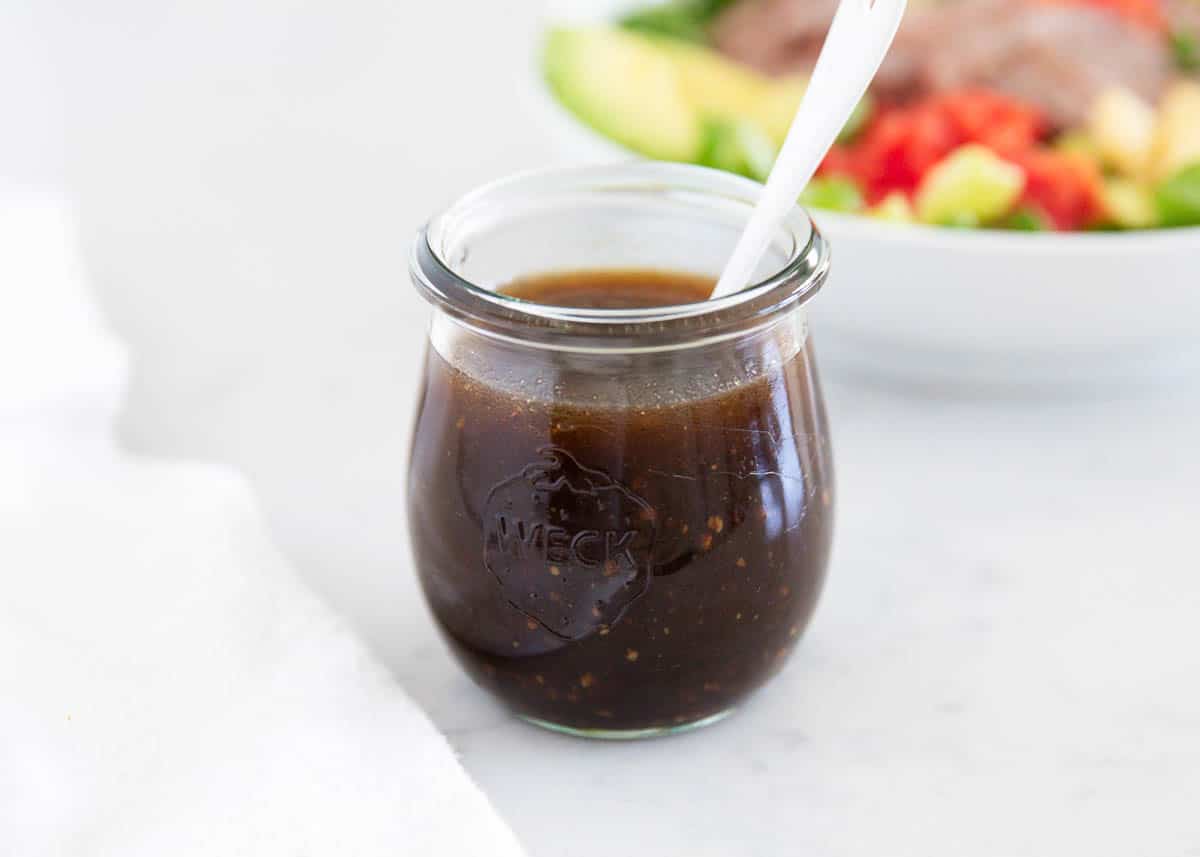 Homemade balsamic dressing in a glass jar with salad.