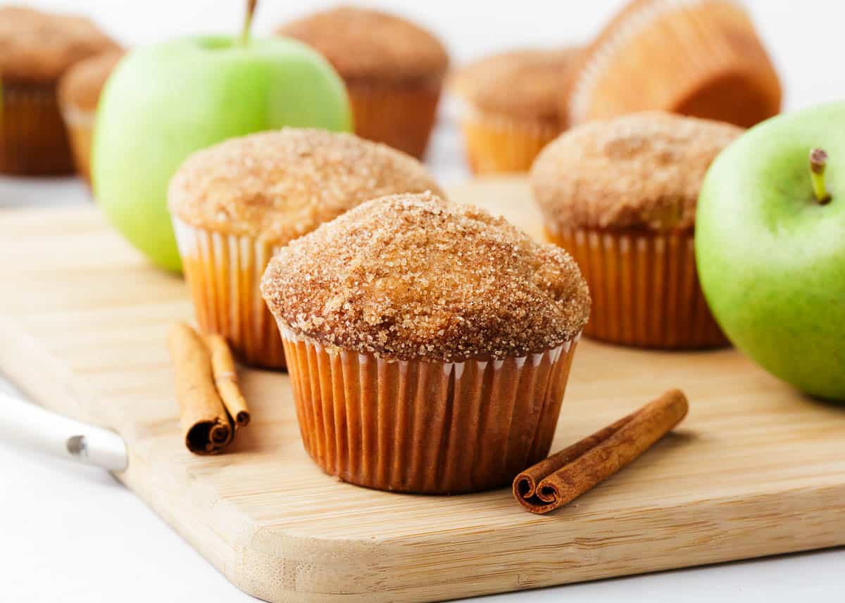 Apple muffins on a wooden cutting board.