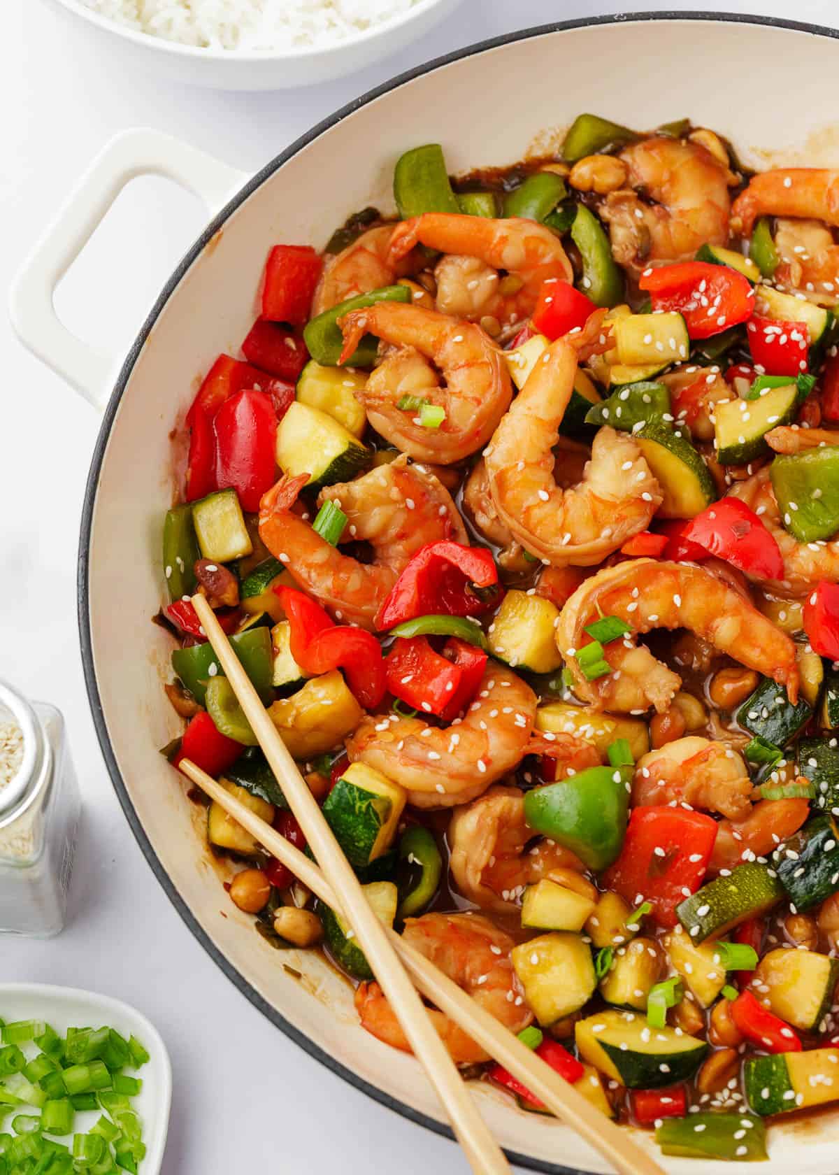 Cooked Kung pao shrimp in a white pot with chopsticks.