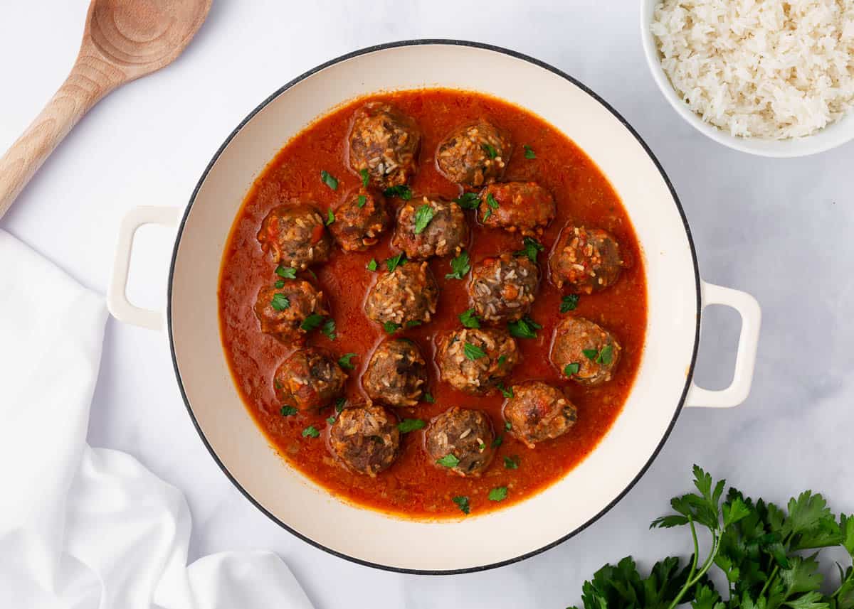 Porcupine meatballs cooking in a white pot.