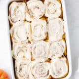 Pumpkin cinnamon rolls in a white baking dish.