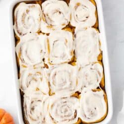 Pumpkin cinnamon rolls in a white baking dish.