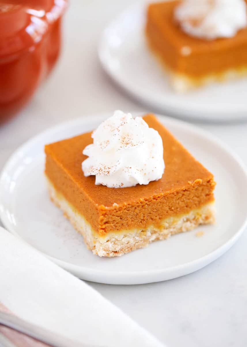 Slice of pumpkin pie bar with whipped cream on top.