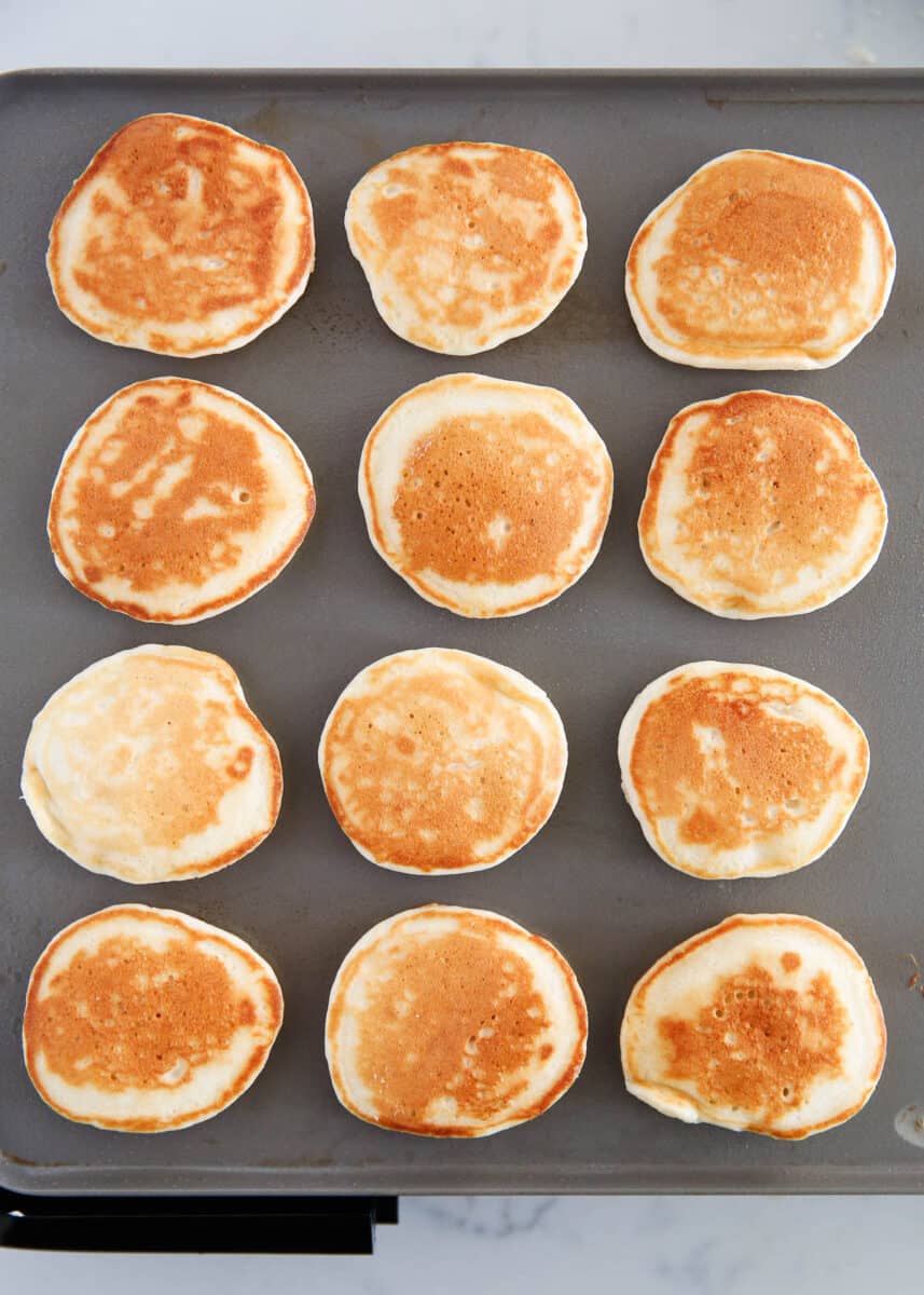 Silver Dollar Pancakes cooking on a griddle.
