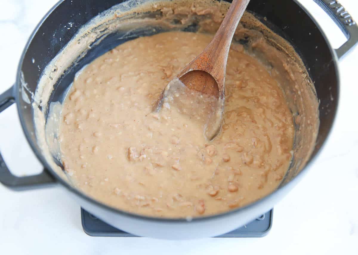 Mashed pinto beans in a pot on the stove.