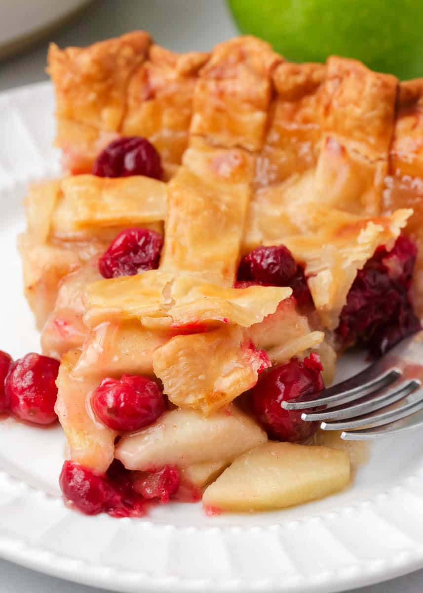 Slice of apple cranberry pie on a plate.