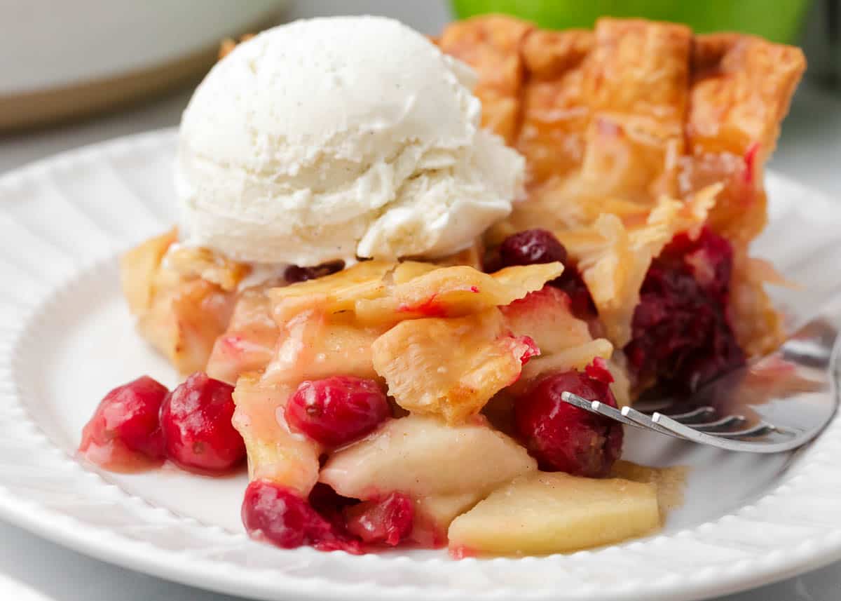 Slice of apple cranberry pie on a white plate.