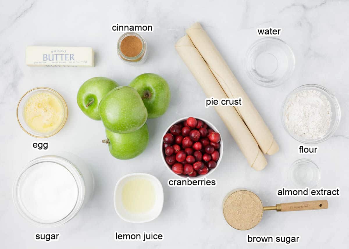 Apple cranberry pie ingredients on a marble counter.
