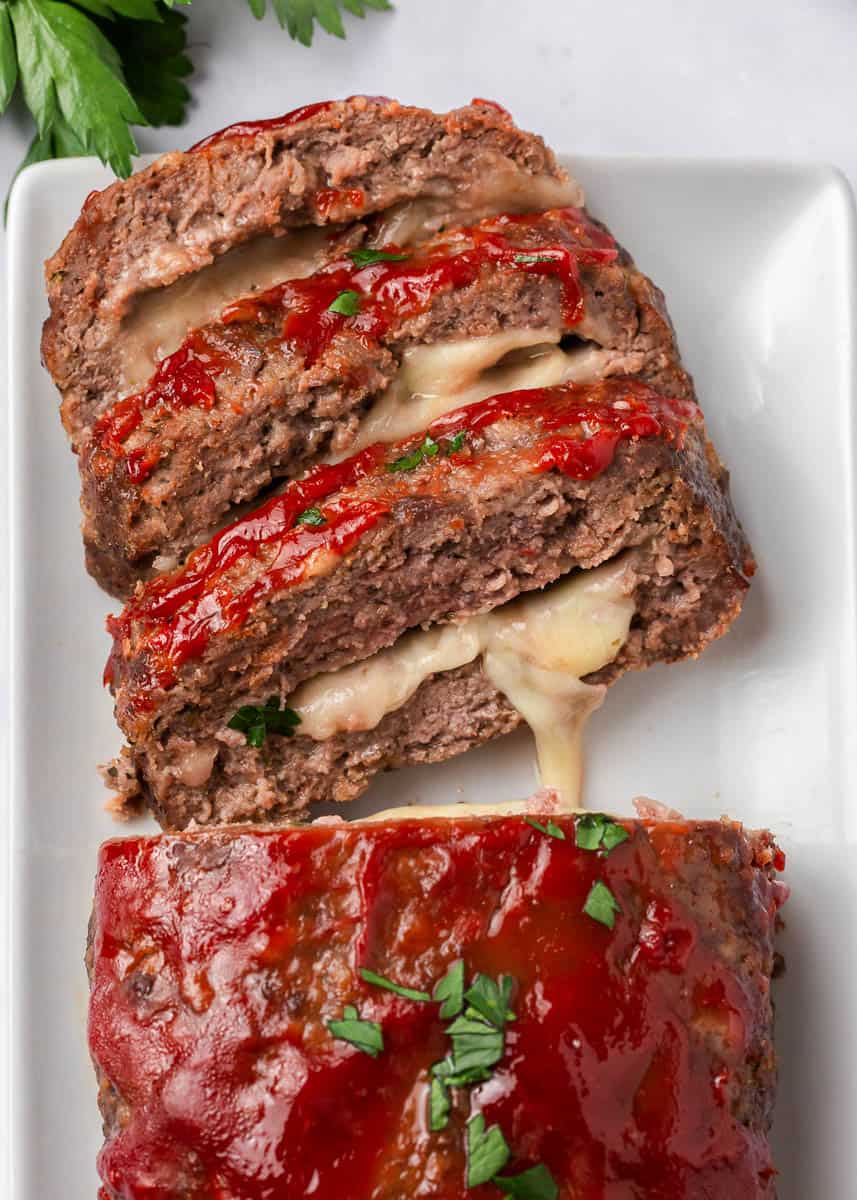 Sliced stuffed meatloaf on a white plate.