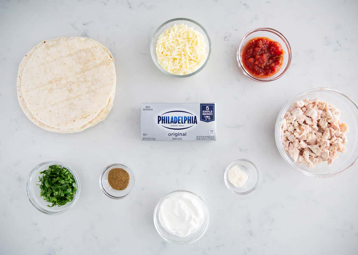 Chicken taquito ingredients on marble counter.