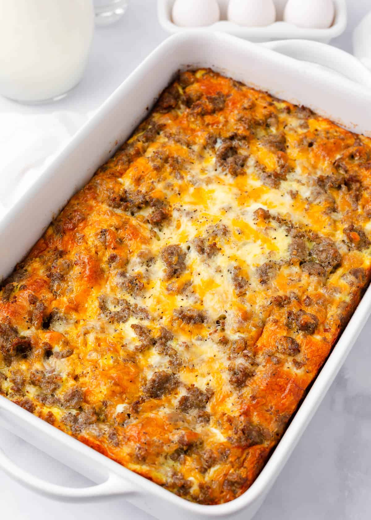 Sausage crescent roll breakfast casserole baked in white baking dish.
