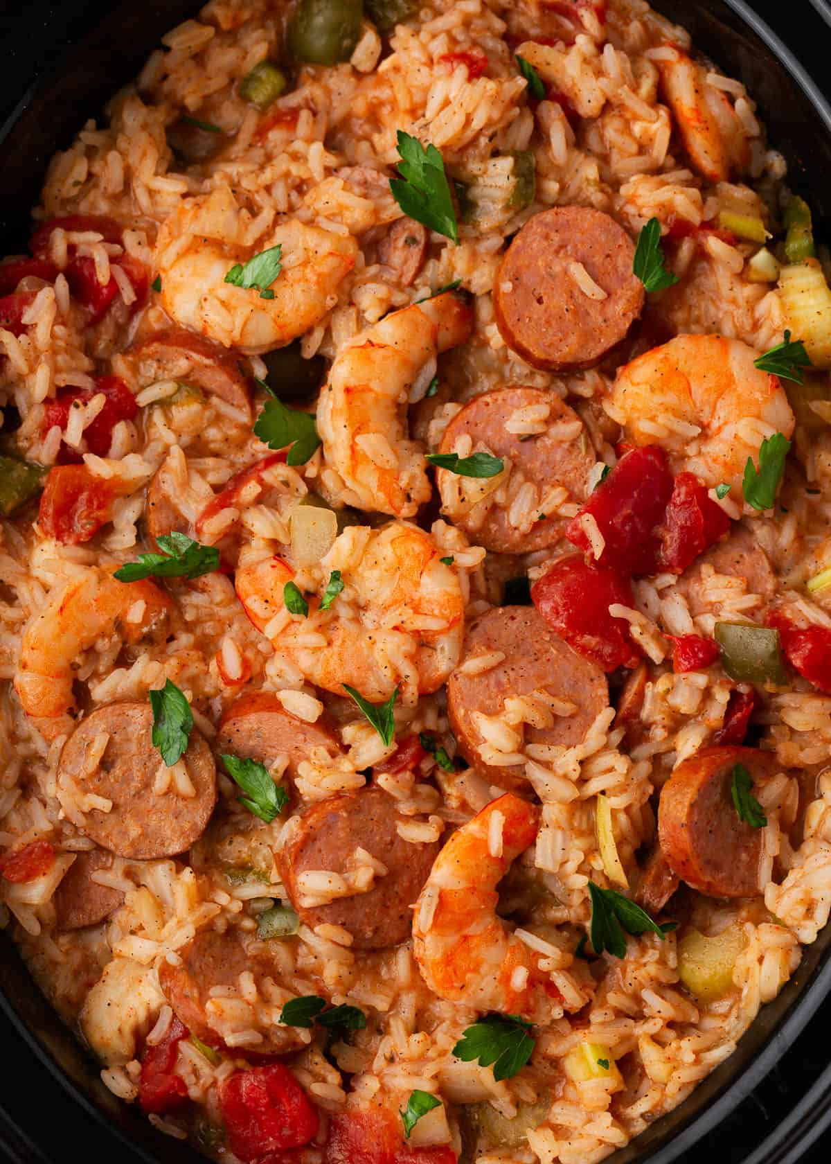 Jambalaya cooked in a black slow cooker.