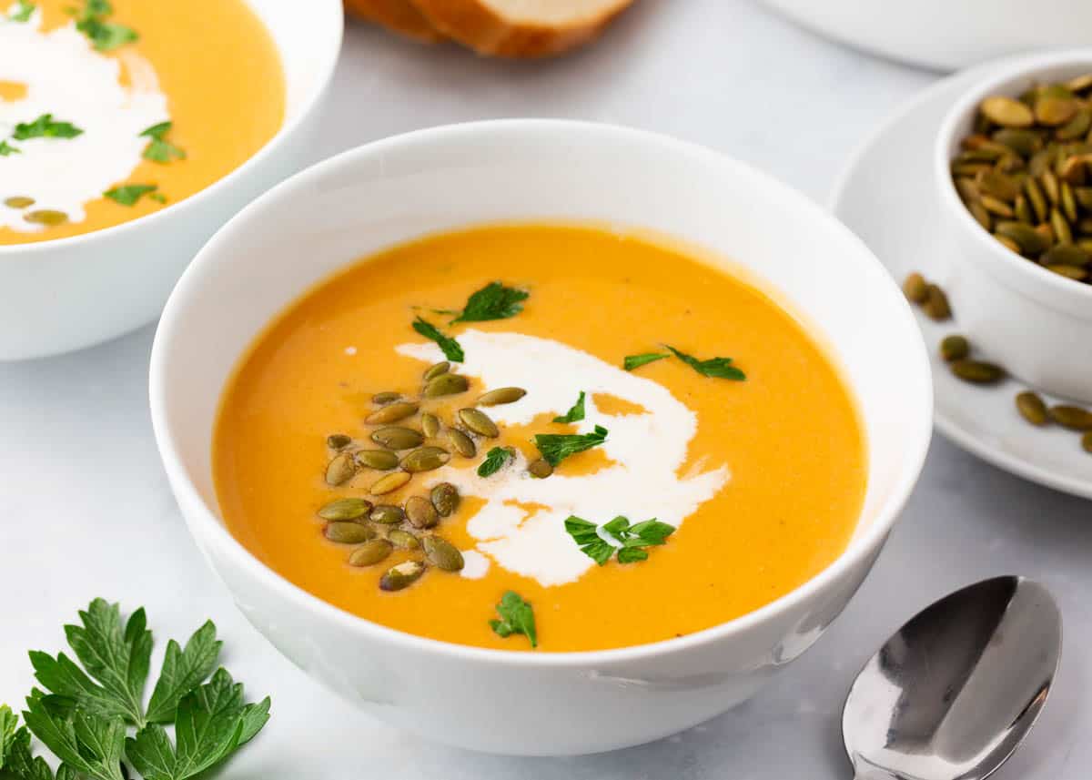 Sweet potato soup in a white bowl with pumpkin seeds.