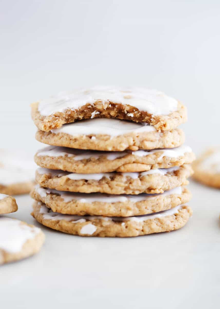 Stacked iced oatmeal cookies on a marble counter.