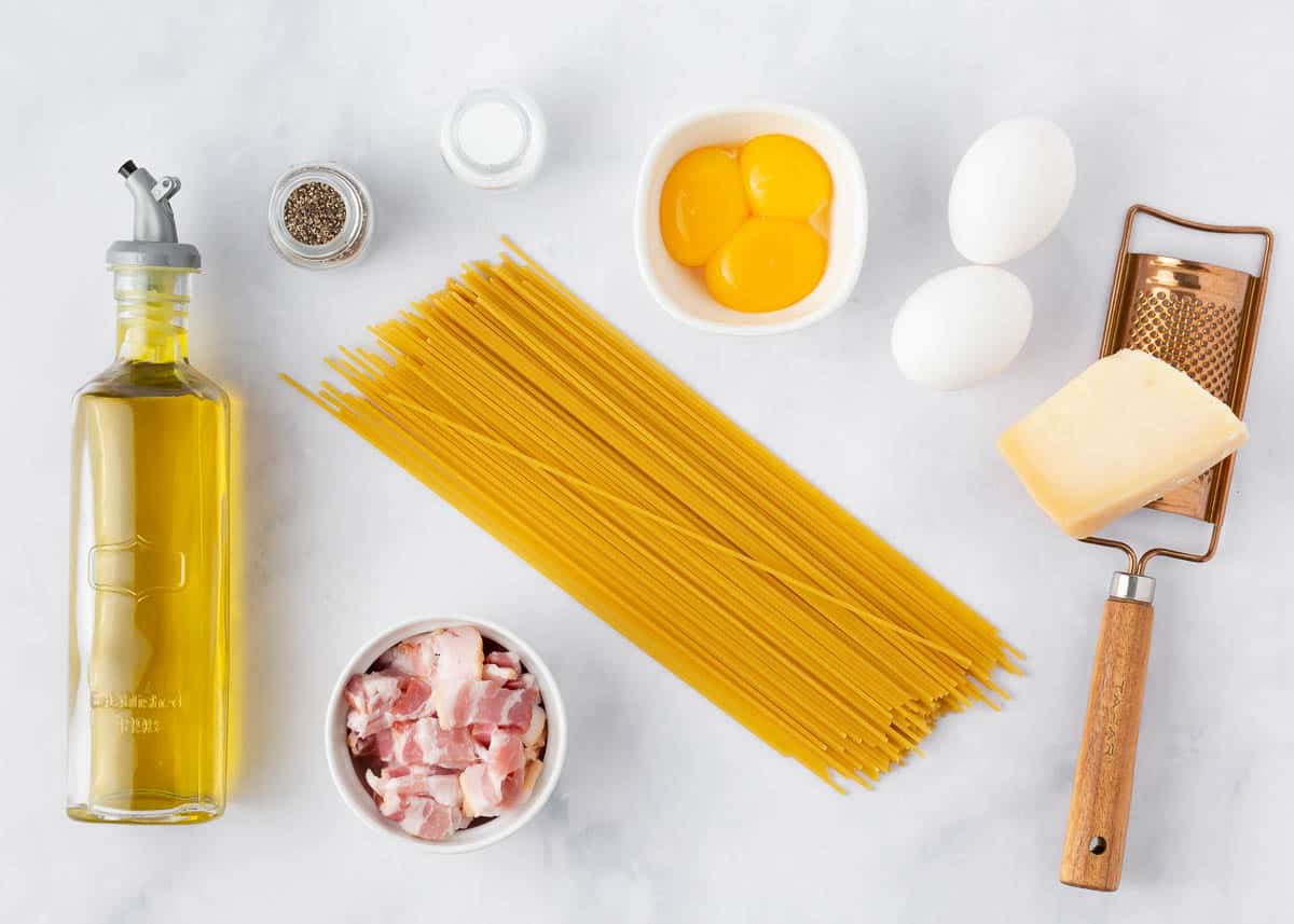 Pasta carbonara ingredients on a marble countertop. 