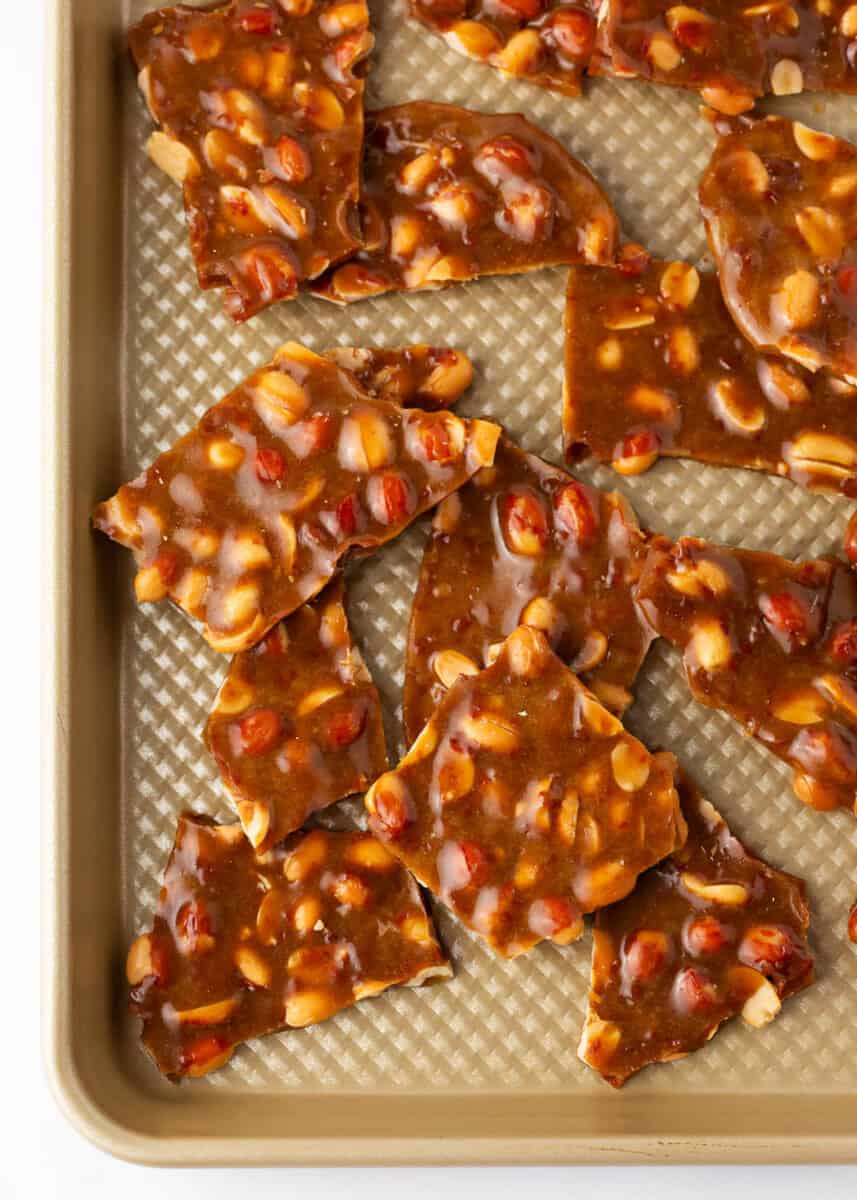 Peanut brittle on a gold baking sheet.
