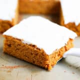 Slice of a pumpkin bar with cream cheese frosting.