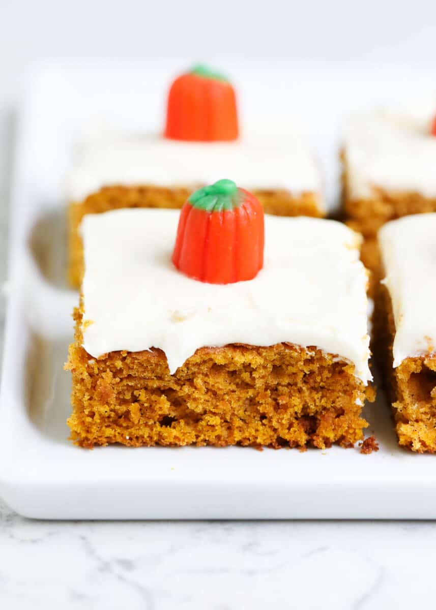 Pumpkin bars with cream cheese frosting and a pumpkins on top.