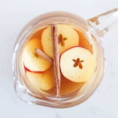 Pitcher full of Thanksgiving punch garnished with apple slices and cinnamon sticks.