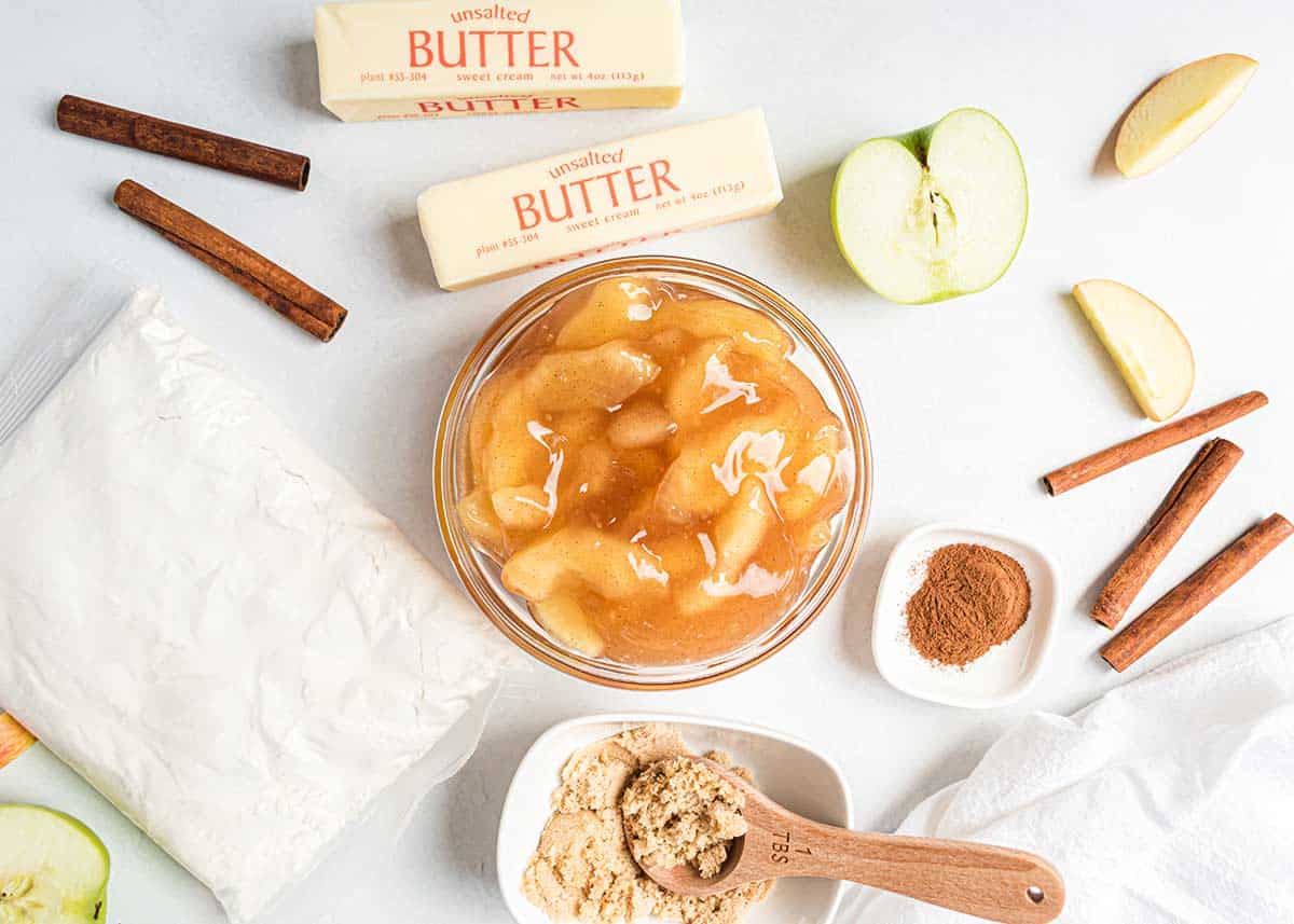 Apple dump cake ingredients including apple pie filling, butter, cake mix and cinnamon.