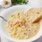 The best ham and potato soup in a white bowl.