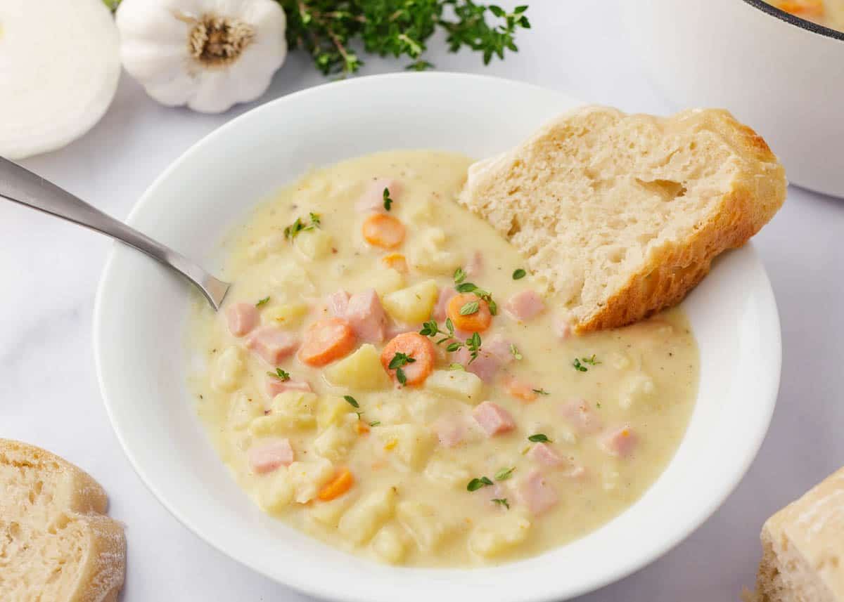 The best ham and potato soup in a white bowl.