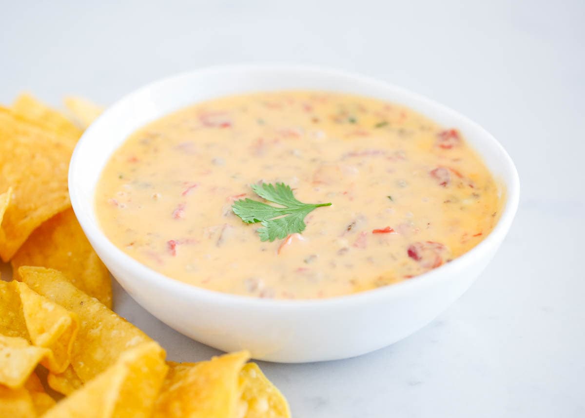 This easy slow cooker party dip is an easy appetizer made with just 5 ingredients, including Velveeta, Rotel, and chunks of juicy sausage. It's a sausage cream cheese Rotel dip that everyone will rave about! Rotel dip in a white bowl.