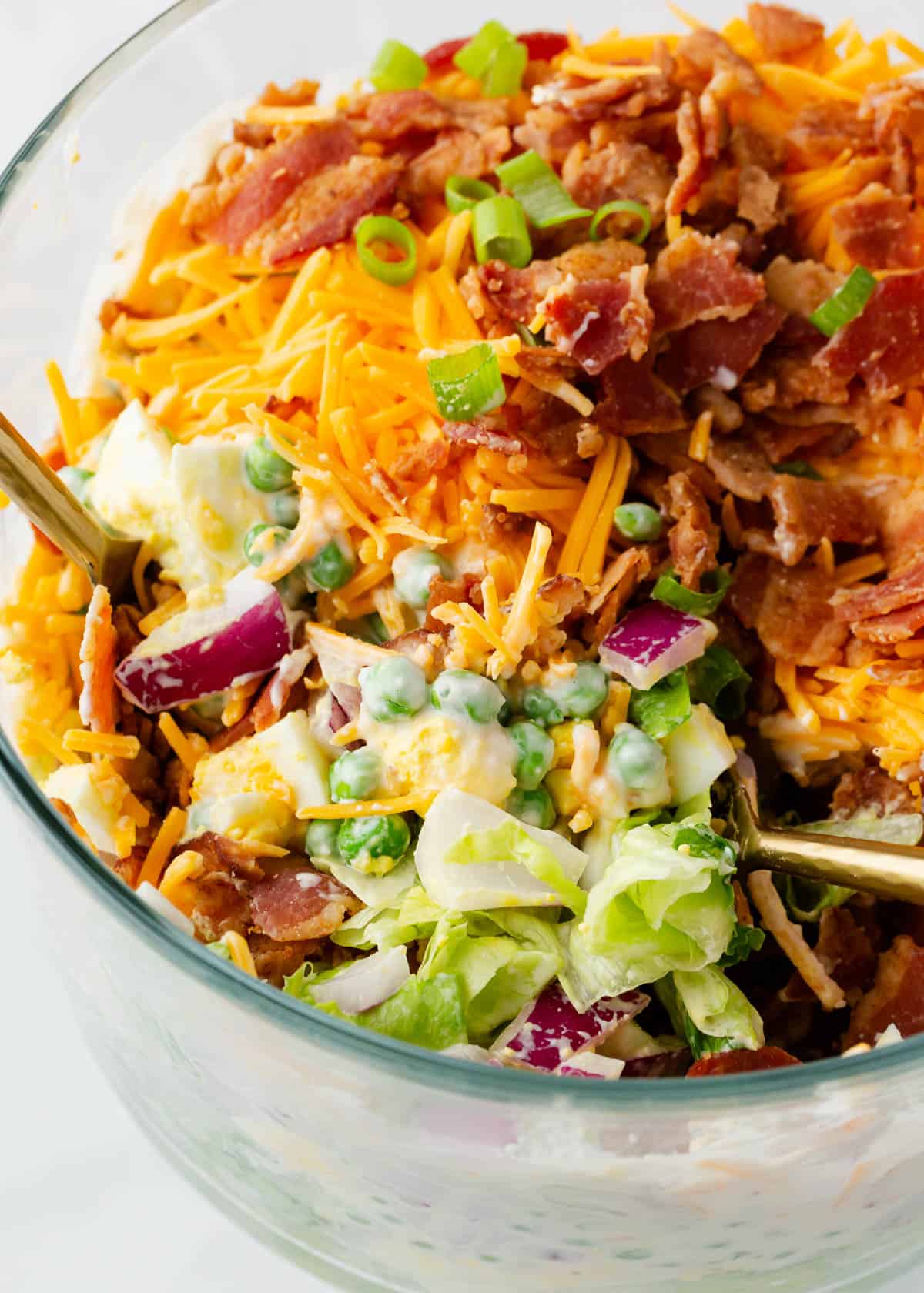 Spoonful of 7 layer salad in glass bowl.