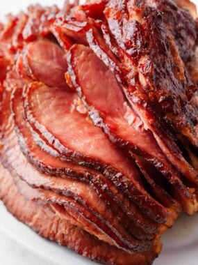 Sliced oven baked ham with brown sugar glaze on a plate for serving.