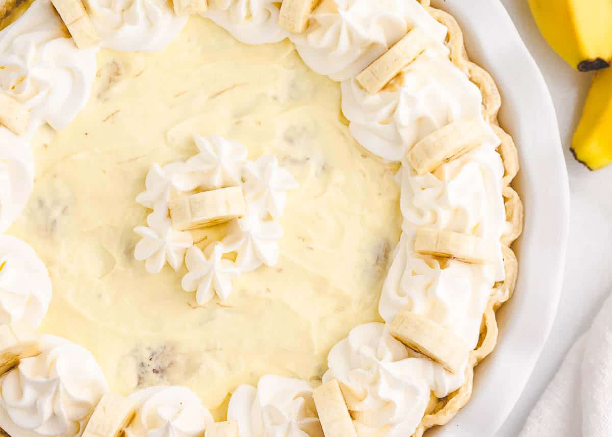 Banana cream pie in white pie dish.