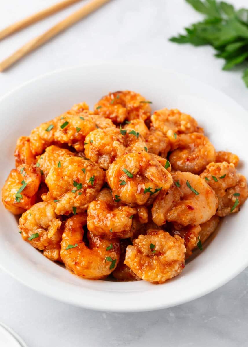 Bang bang shrimp in a white bowl with parsley.