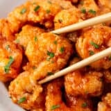 Bang bang shrimp in a white bowl with chopsticks.