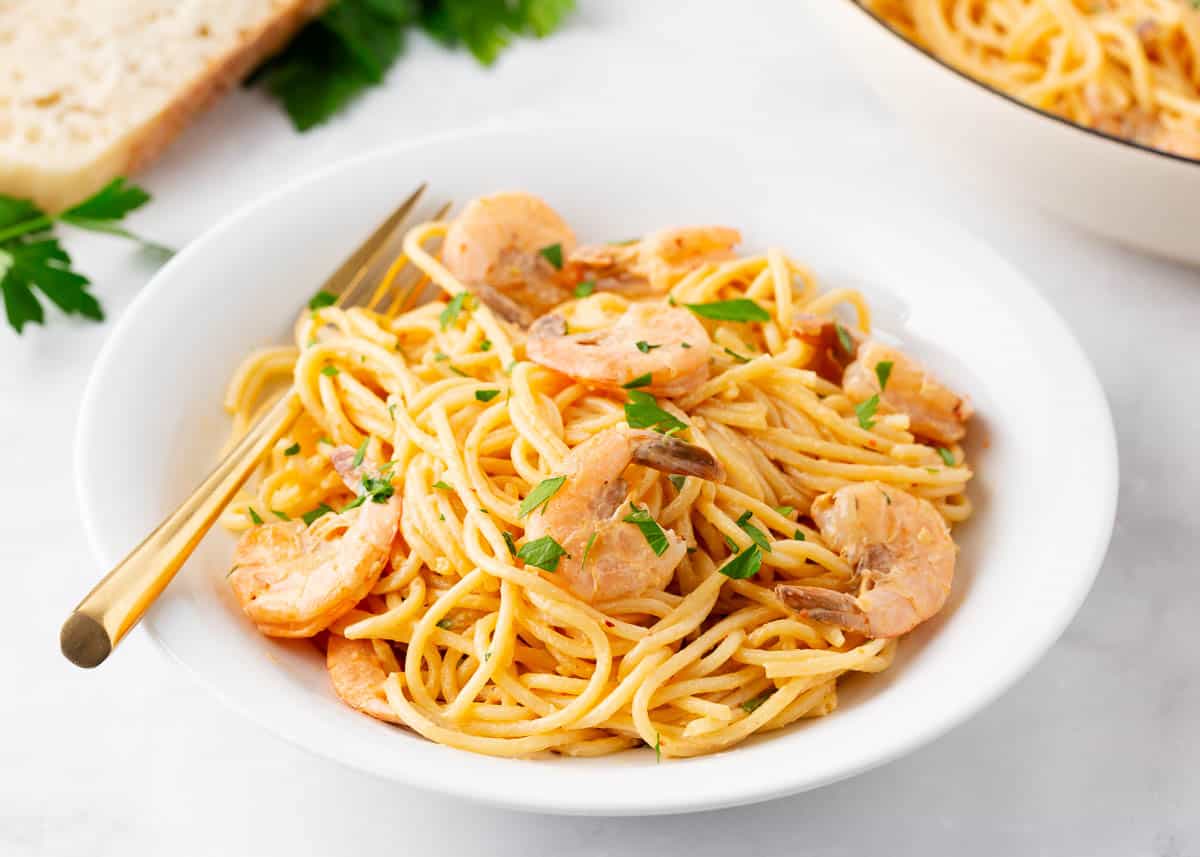 Bang bang shrimp pasta in a white bowl with fork.