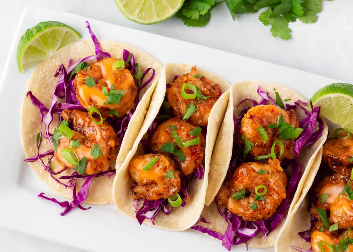 Bang bang shrimp tacos on a white plate.