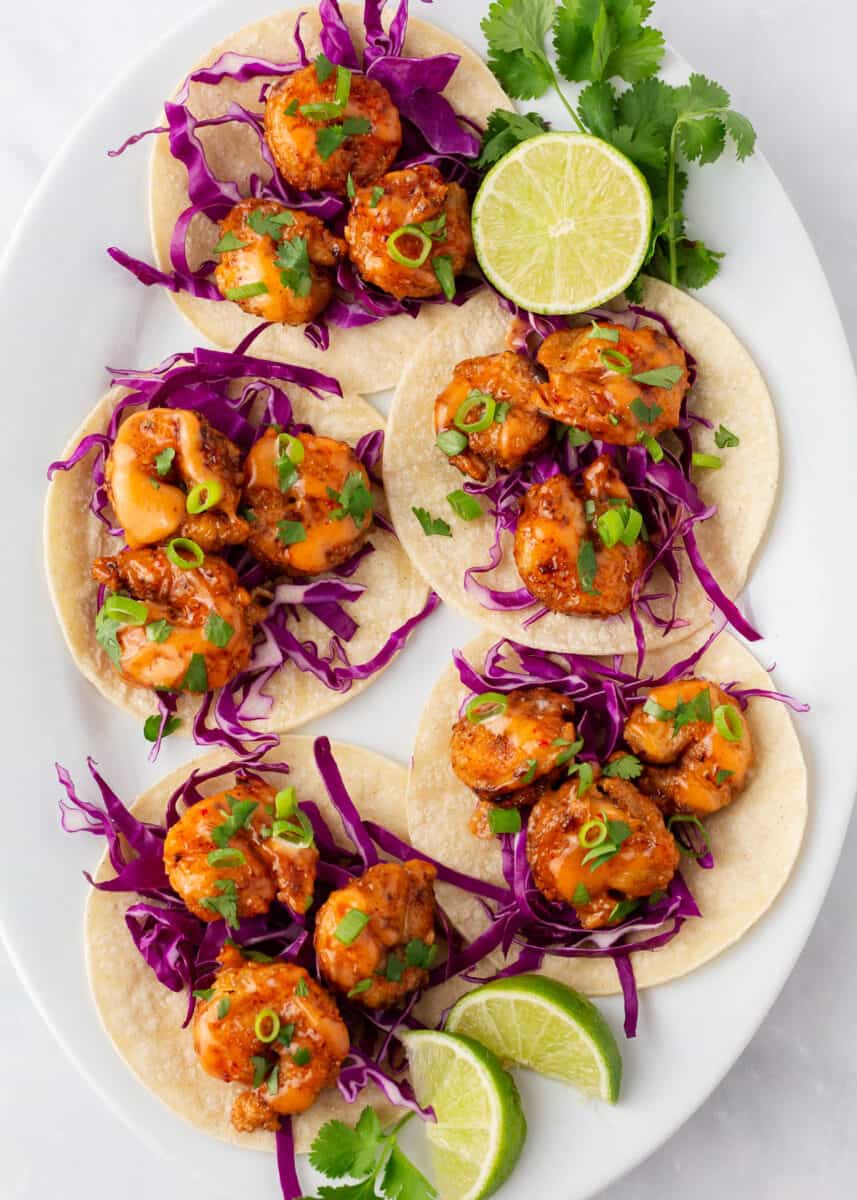 Bang bang shrimp tacos on a white platter.