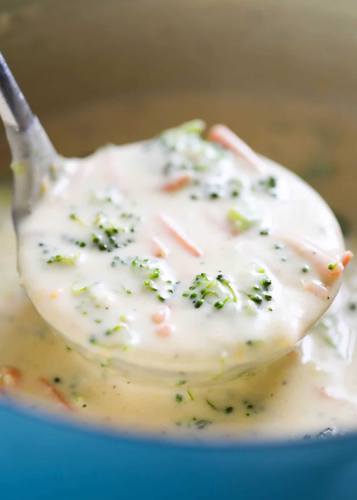 A full ladle lifting the broccoli cheese soup from the dutch oven. 