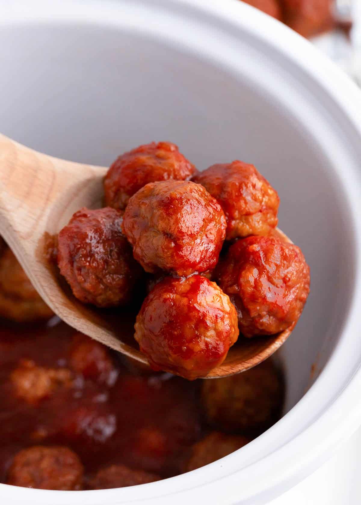 Up close photo of the cranberry meatballs on a wooden spoon. 