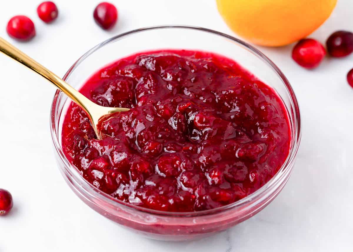 Cranberry sauce in a glass bowl with spoon.