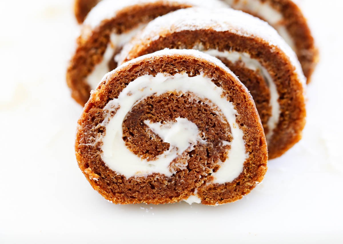 Delicious layers of fluffy pumpkin cake and sweet cream cheese filling swirled together to make the ultimate treat! This easy pumpkin roll is perfect to serve during the fall season. Sliced pumpkin roll on counter.