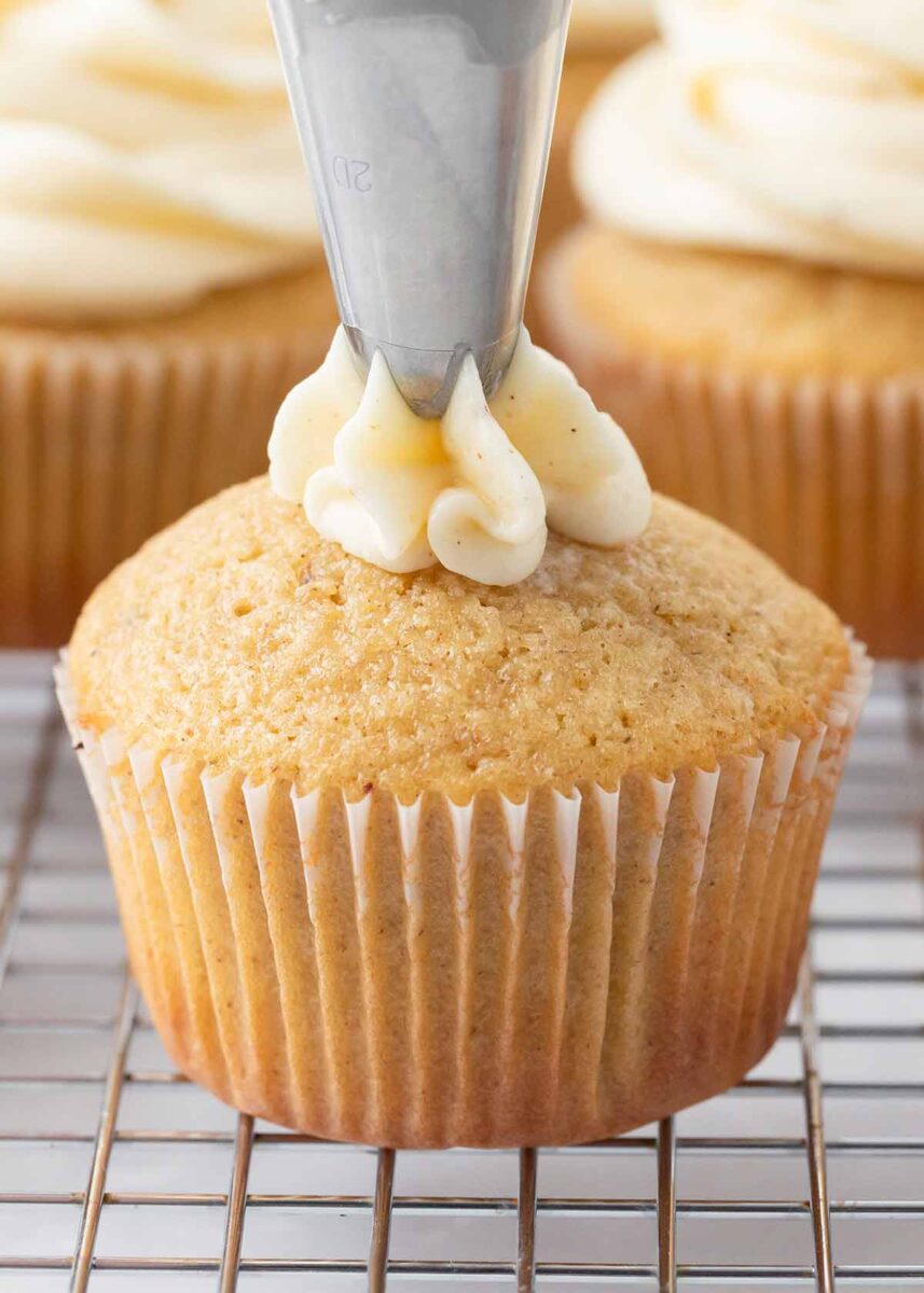 Piping eggnog frosting on a cupcake.