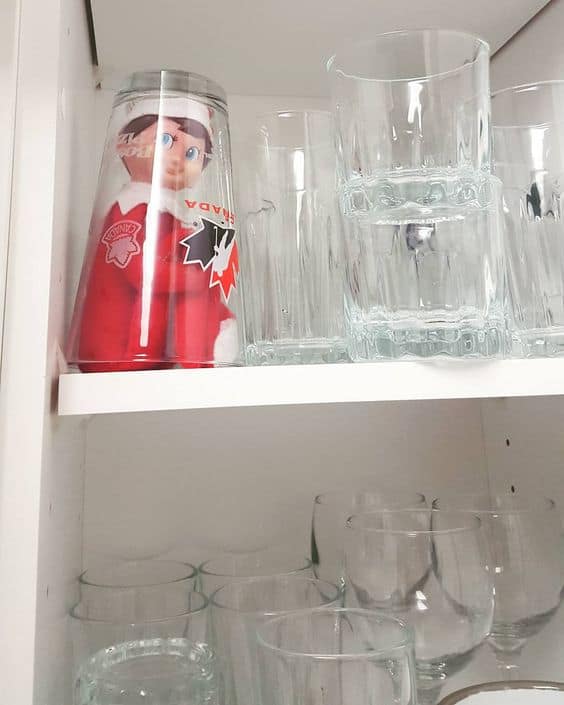 Elf sitting under a glass cup. 