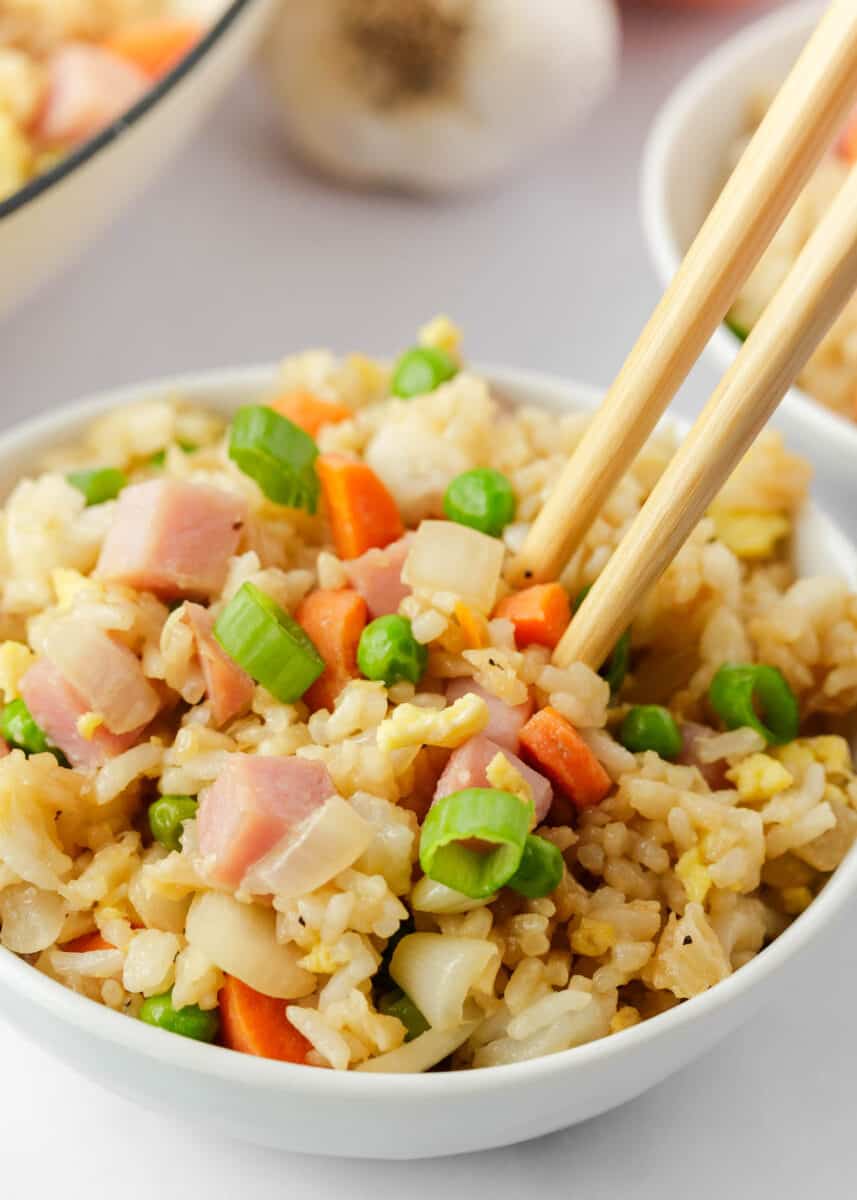 Ham fried rice in a white bowl with chopsticks.