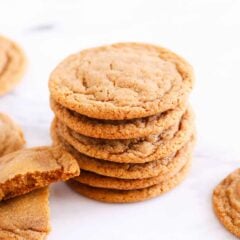 A stack of ginger molasses cookies with one broken in half to show chewy texture.